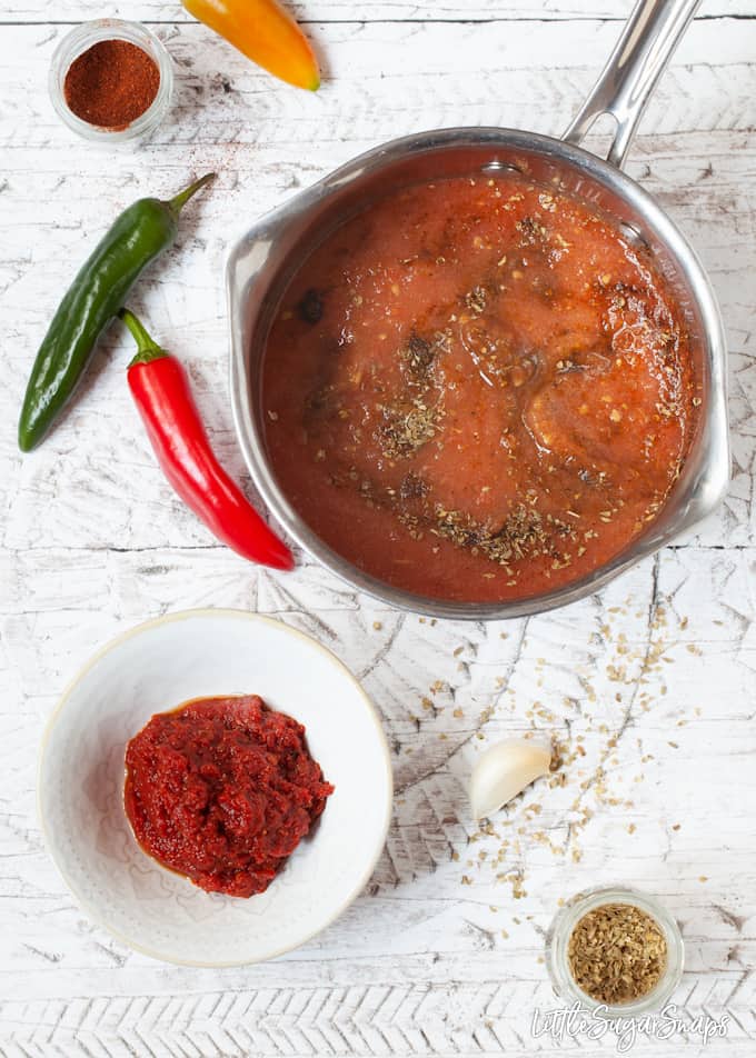 Cooked tomato salsa in a bowl and a pan with uncooked ingredients.