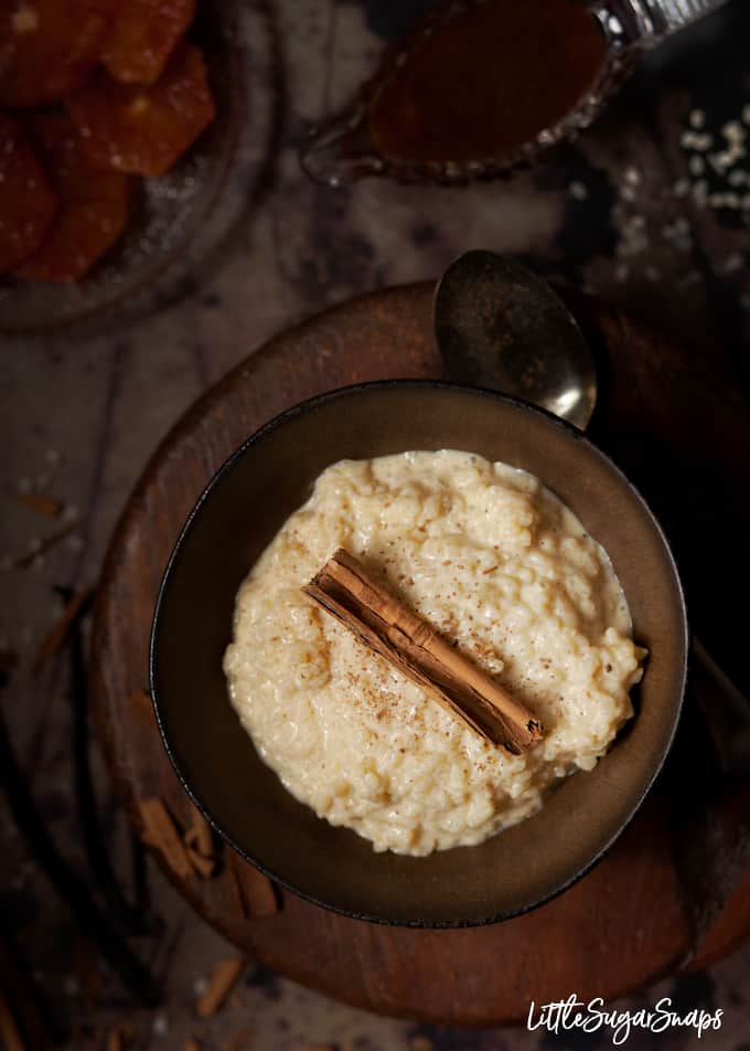 Rice pudding in a bowl with a cinnamon stick and grated cinnamon. 