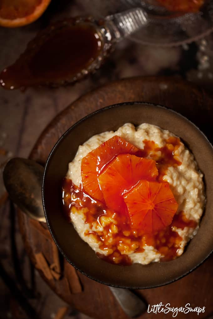 A bowl of rice pudding topped with blood orange slices in caramel sauce.