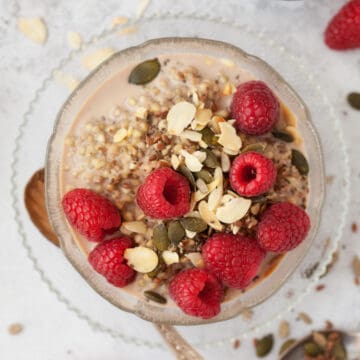 Close-up of a bowl of buckwheat porridge with raspberries and pumpkin seeds.