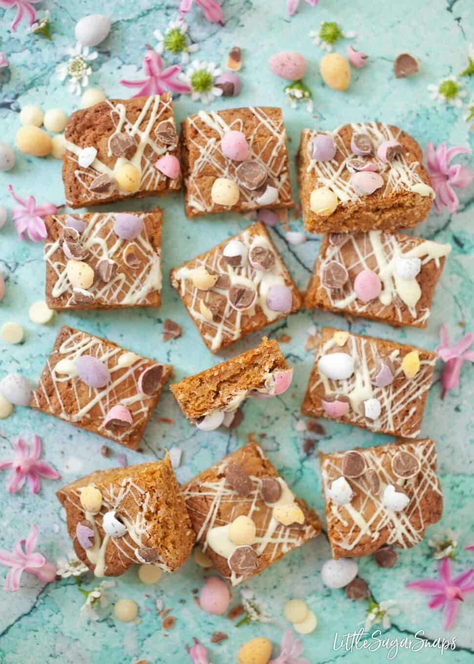 Squares of mini egg blondies topped with mini eggs and white chocolate.