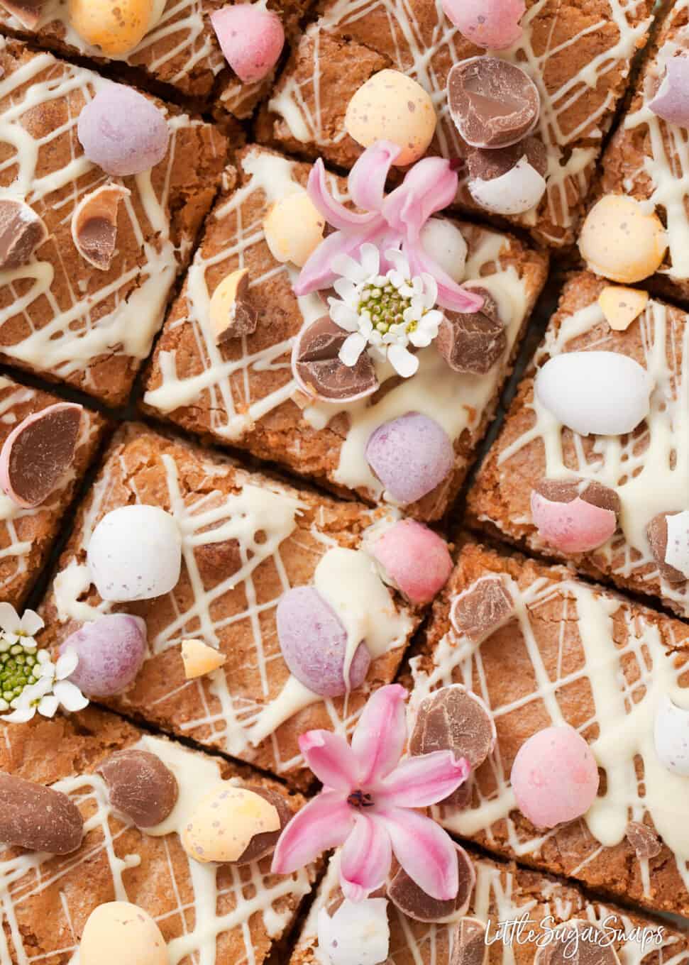 close up of mini egg blondies with white chocolate drizzle and chopped candy eggs.