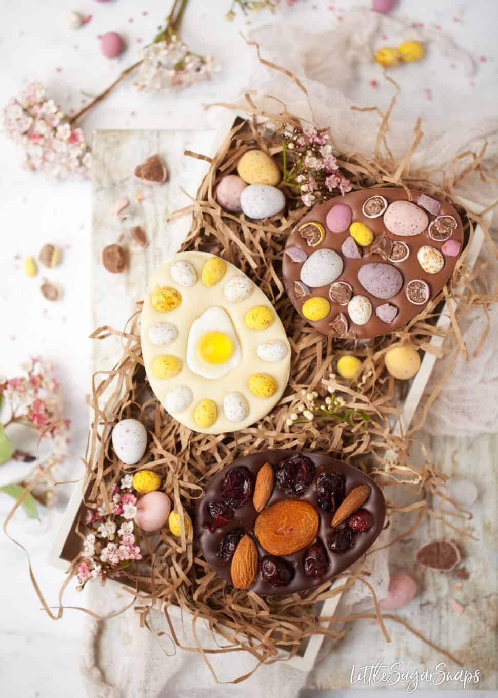 A tray of homemade easter eggs with flowers and chocolate mini eggs in the tray