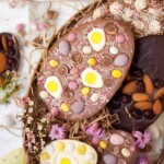Homemade chocolate easter eggs decorated with fruit, nuts, jelly sweets and mini eggs