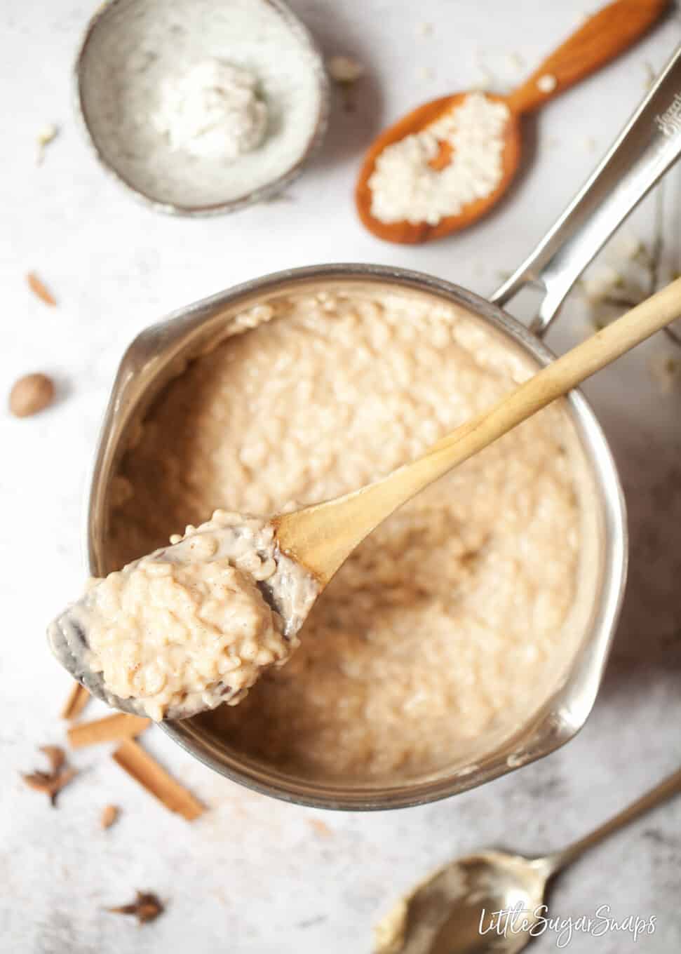 A pan of vegan rice pudding with a wooden spoon resting on top
