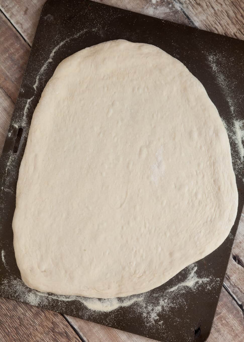 a pizza base on a baking sheet dusted with semolina ready for toppings to be added