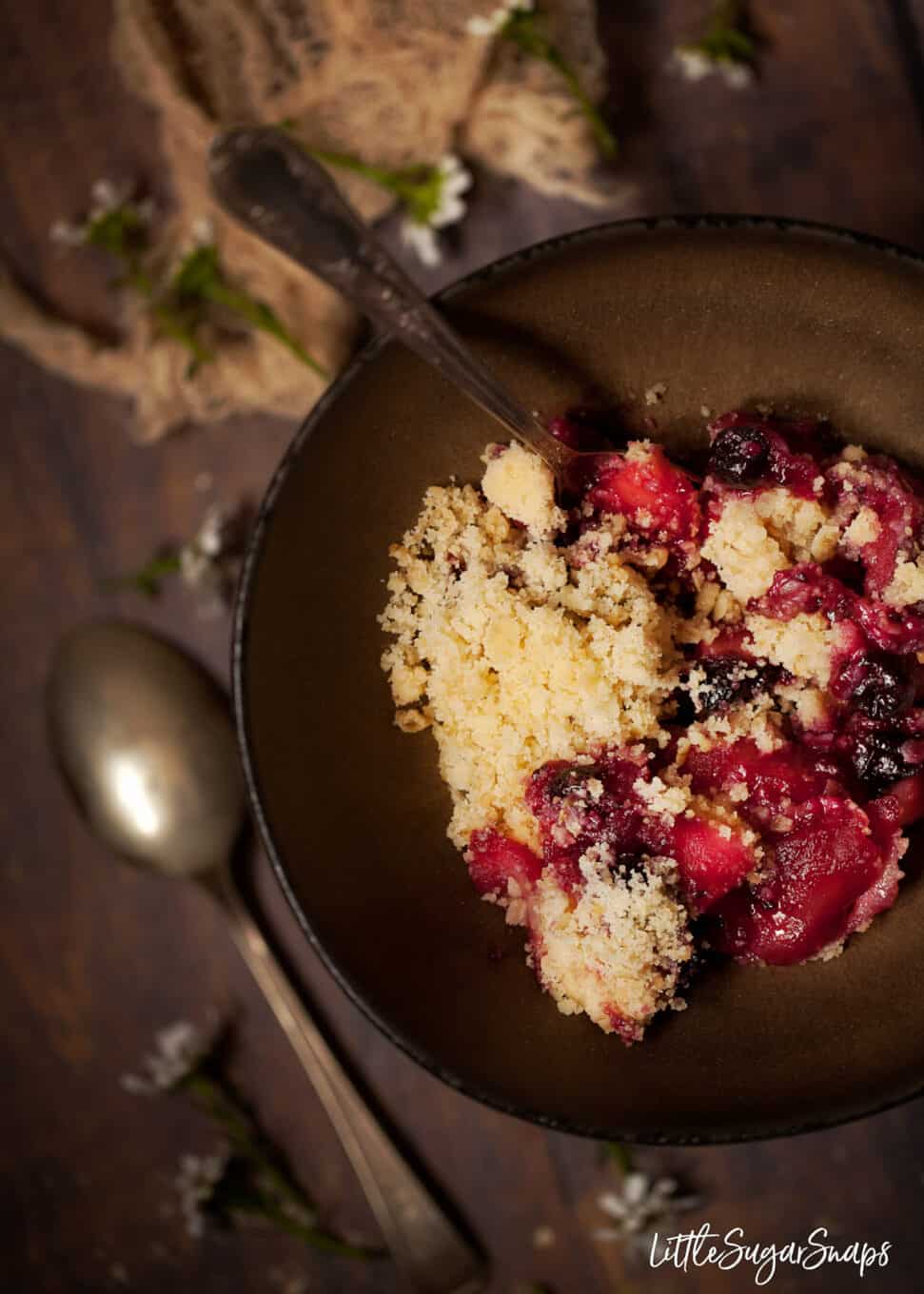 Close up of apple and blackcurrant crumble in a bowl in a rustic setting