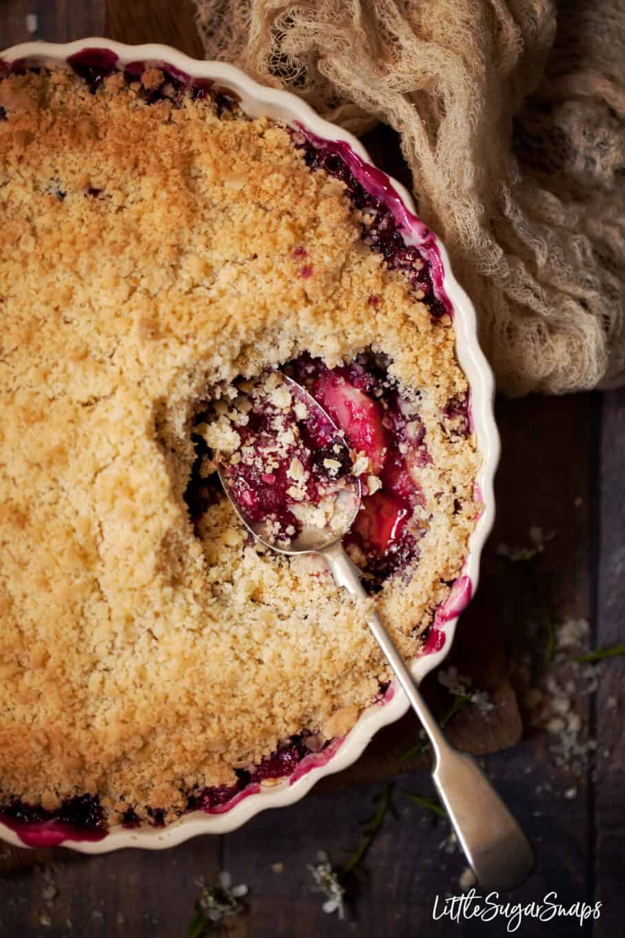 A serving dish filled with apple and blackcurrant crumble.