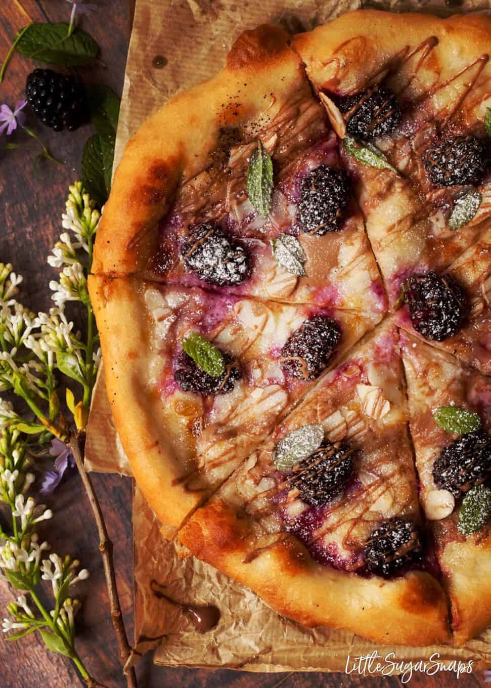 Overhead view of recipe for dessert pizza topped with soft cheese and berries. 