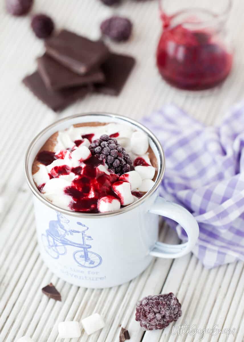 Hot chocolate topped with cream, marshmallows,fruit sauce & frozen blackberry