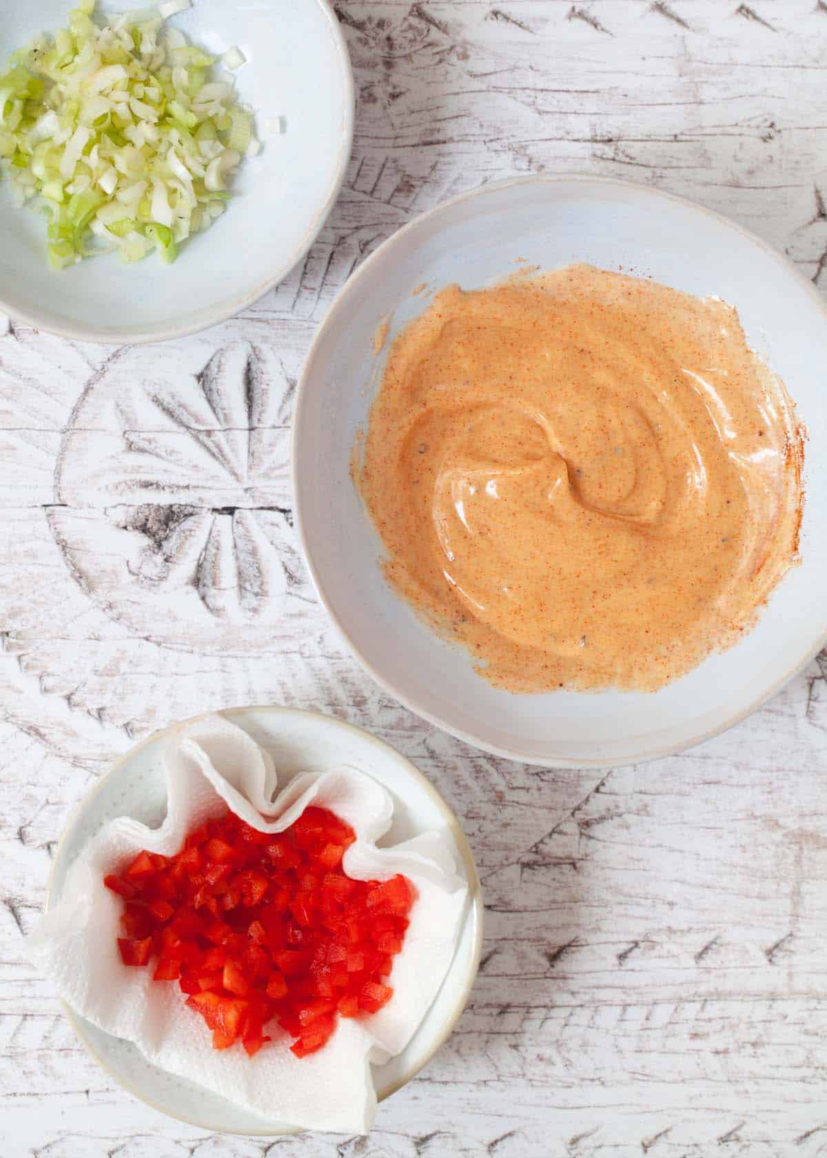 Paprika mayonnaise mixed in a shallow bowl with onion and red pepper alongside