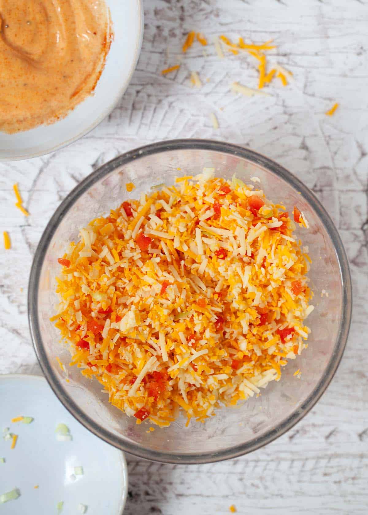 Mixed grated cheese in a bowl with salad onion and red pepper mixed in.