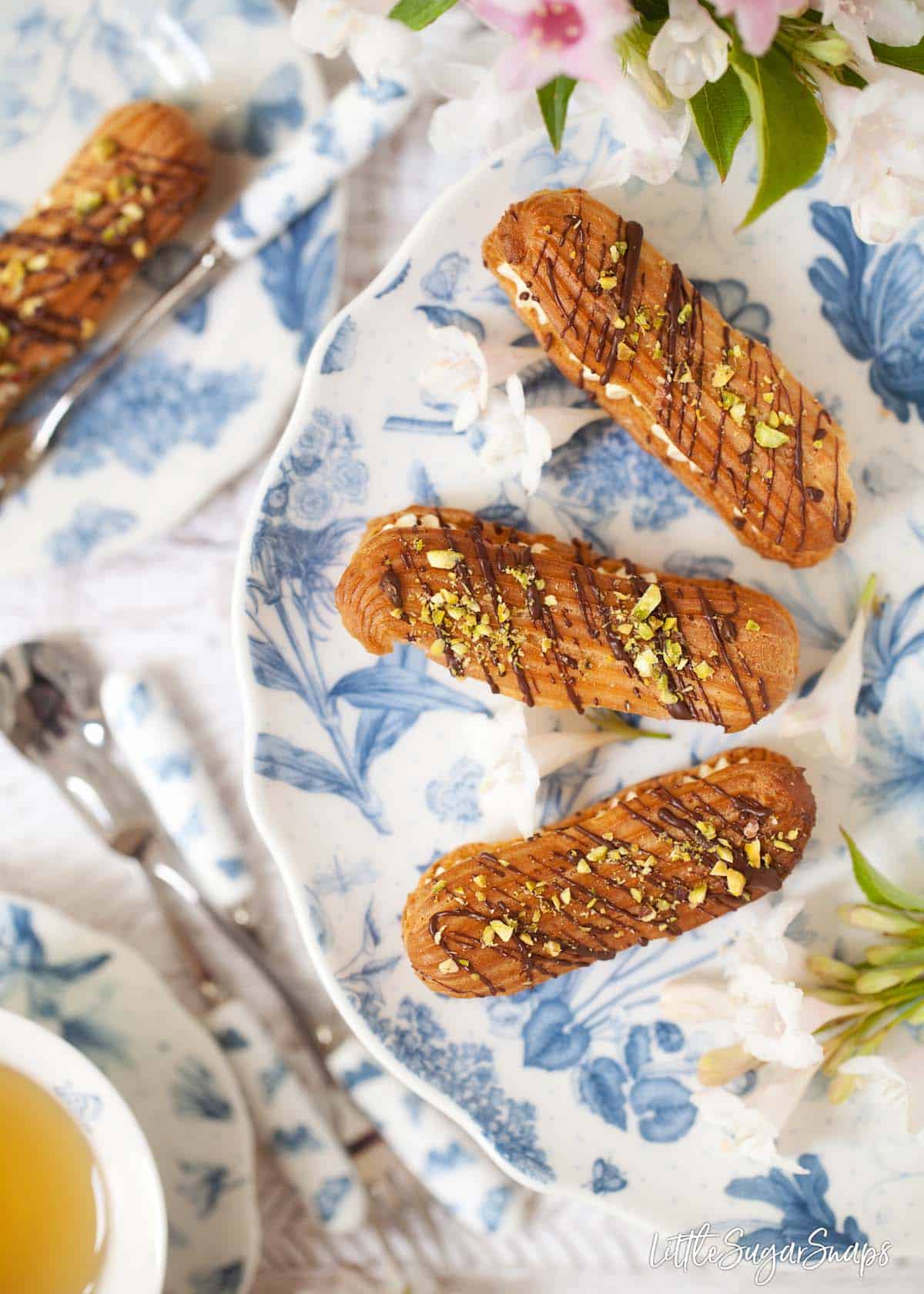 Three Eclairs on a blue and white cake stand. 