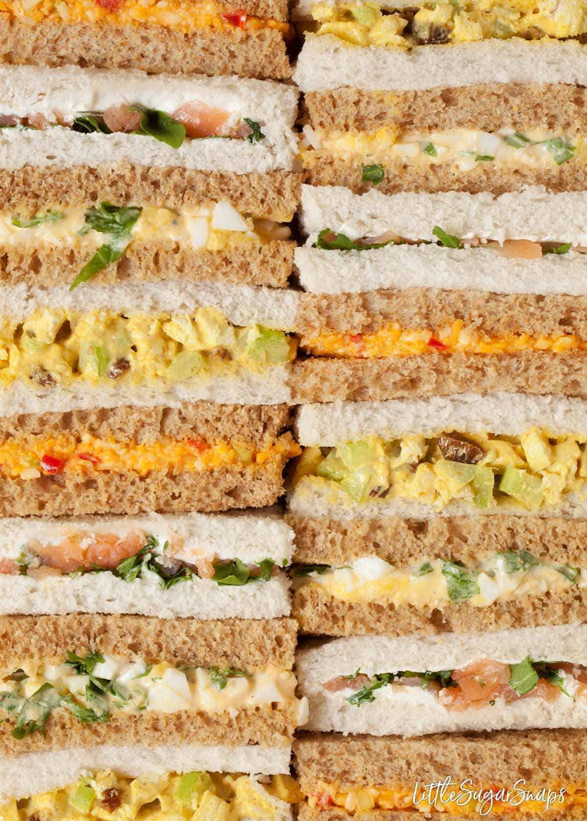 Two rows of afternoon tea sandwiches with various fillings 