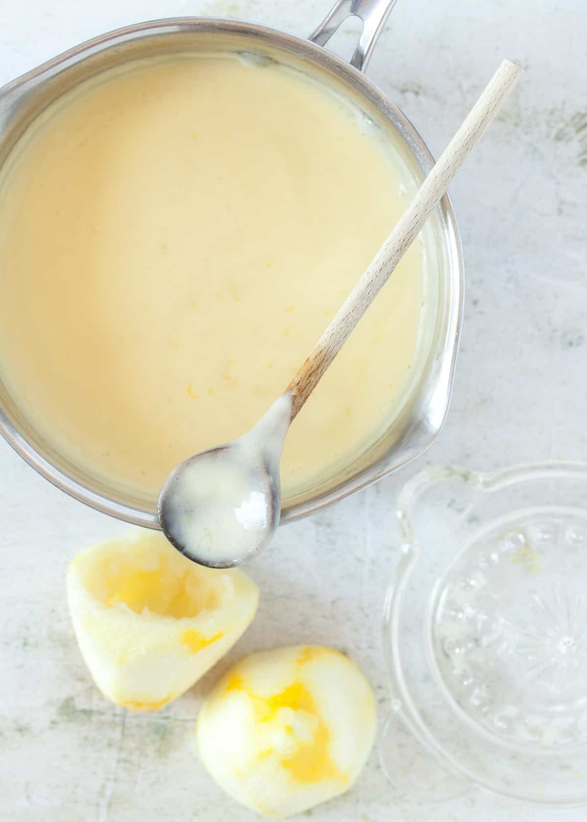 Lemon posset thickened in a saucepan with a wooden spoon resting across it