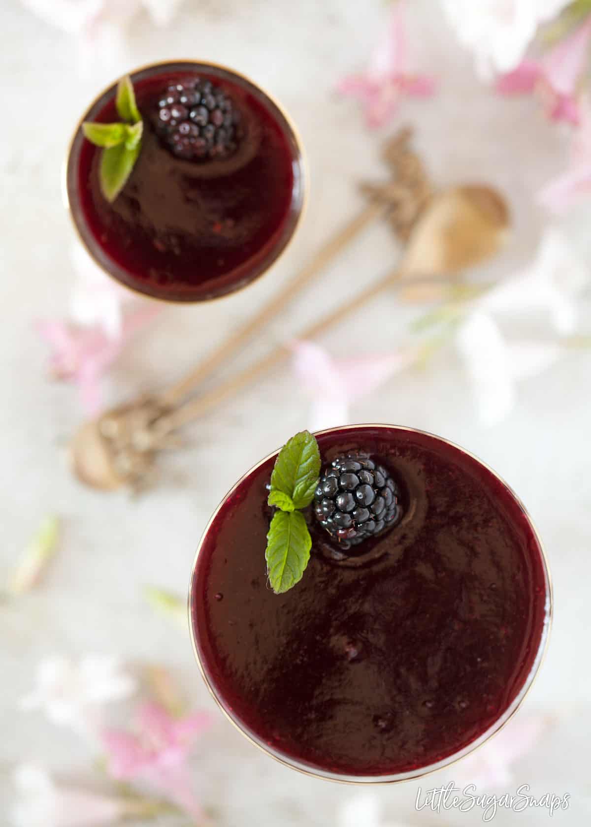 Overhead view of two glasses holding blackberry deserts