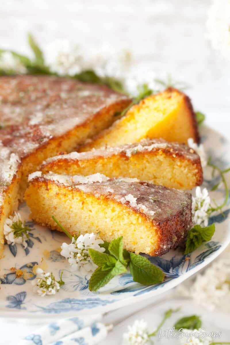 Close up of slices of orange semolina cake garnished with sugar and mint.