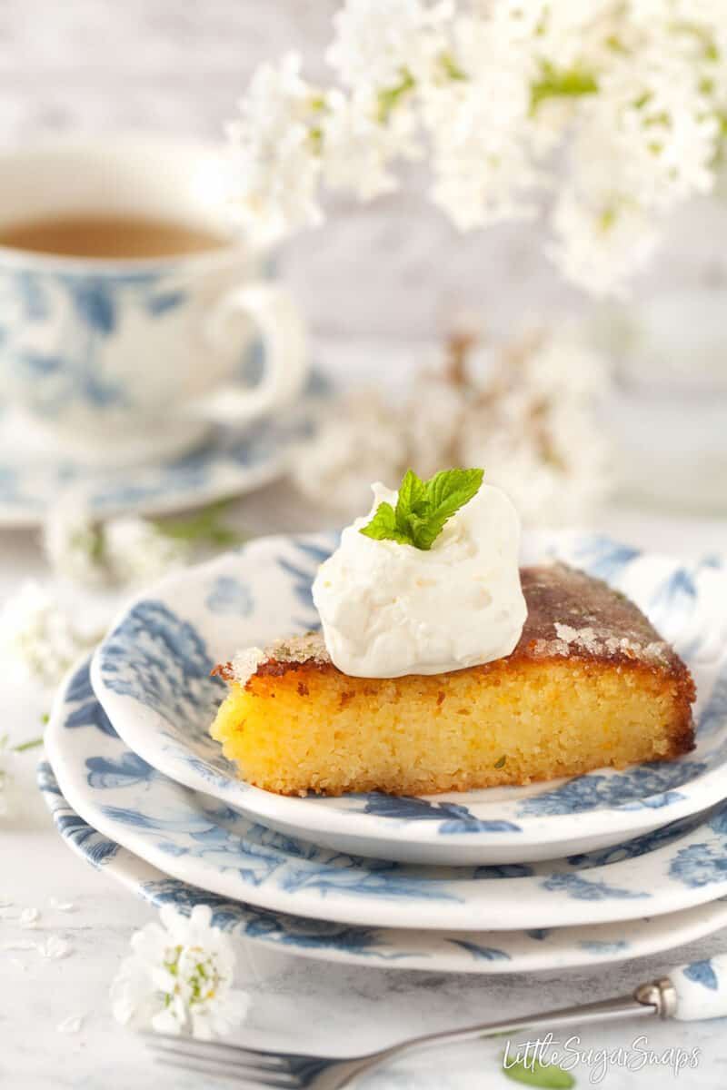 A slice of orange and semolina cake topped with chantilly cream. 