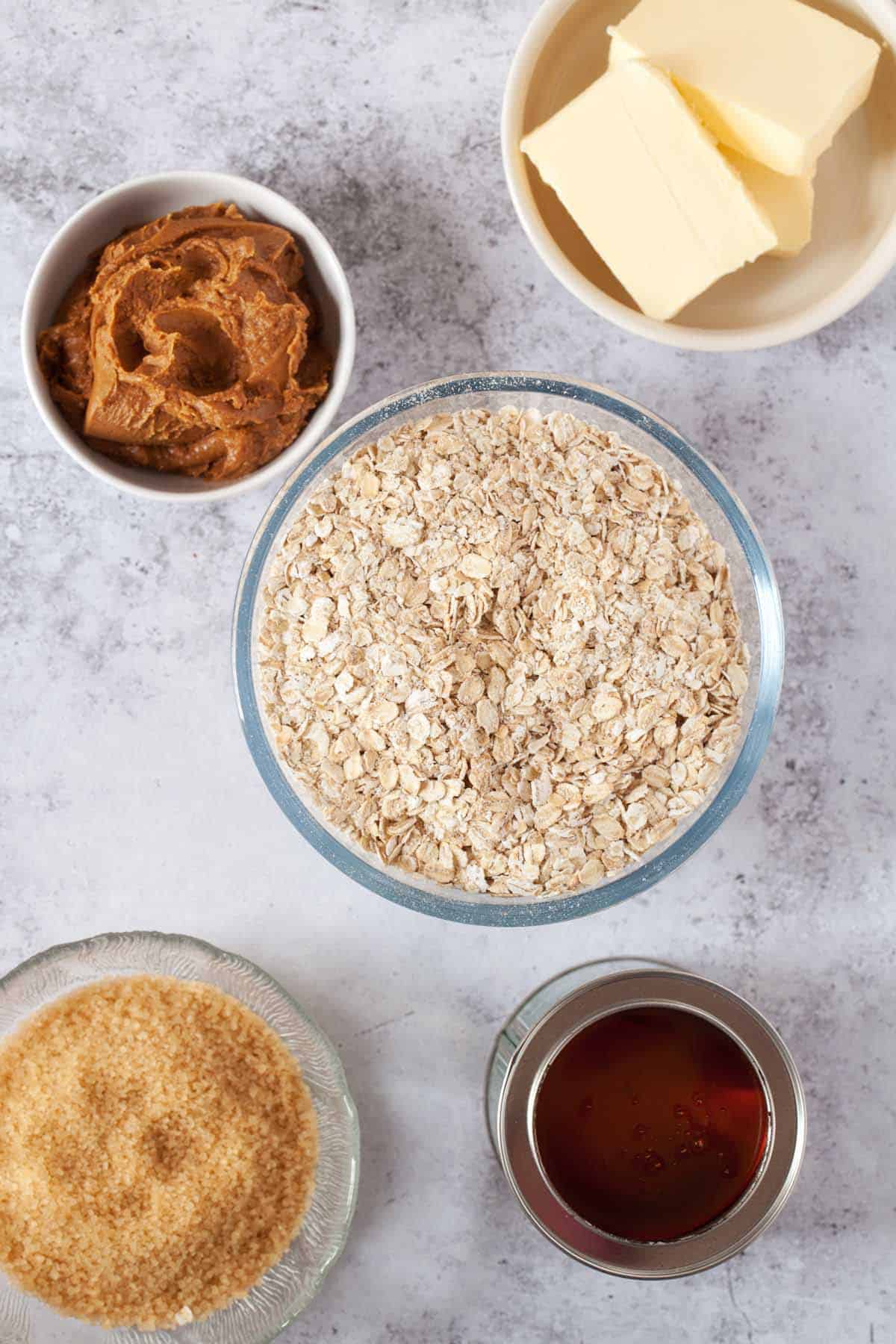 Ingredients in bowls - oats, butter, Biscoff spread, syrup and sugar