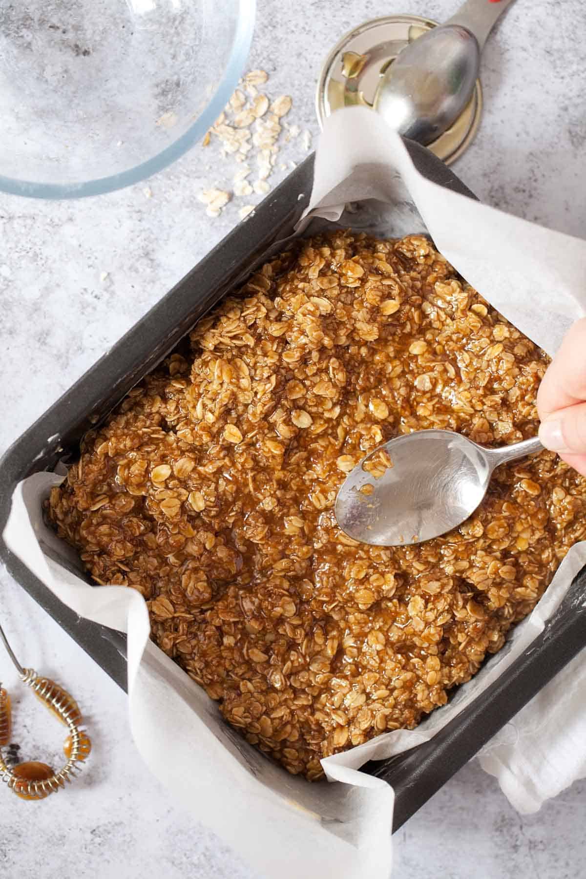 Spreading Biscoff flapjack mixture into a pan ready for baking