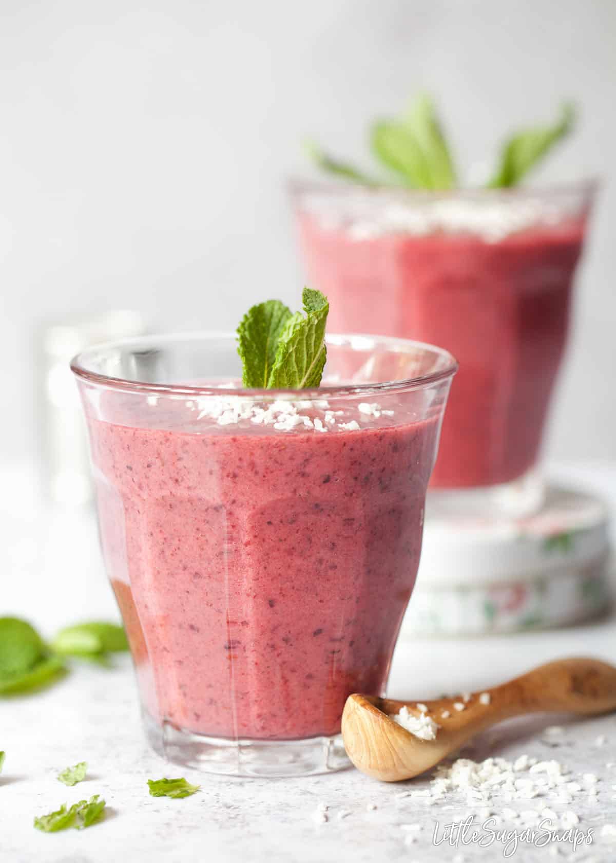 Blackcurrant smoothies in glasses. Garnished with dessicated coconut and mint leaves