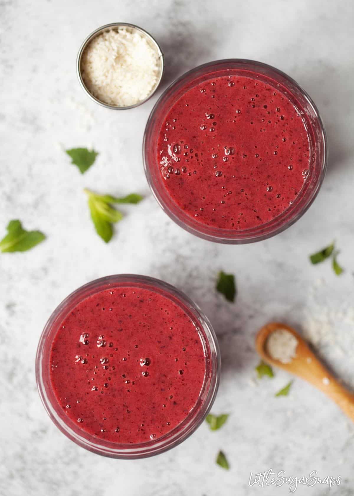 Overhead view of 2 glasses of blackcurrant smoothie.