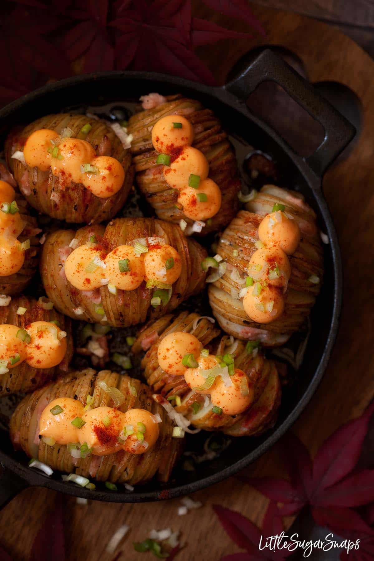 Cheesy Hasselback potatoes filled with bacon and topped with cheese spread and onion