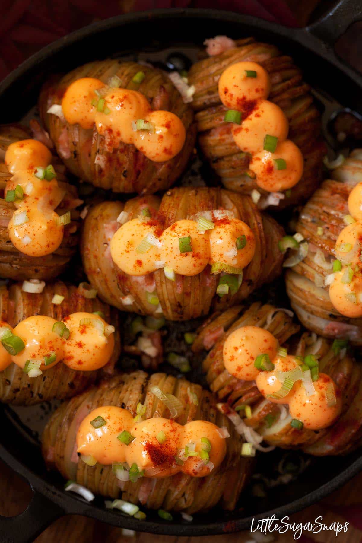 Close up of cheesy hasselback potatoes filled with bacon and topped with cheese spread