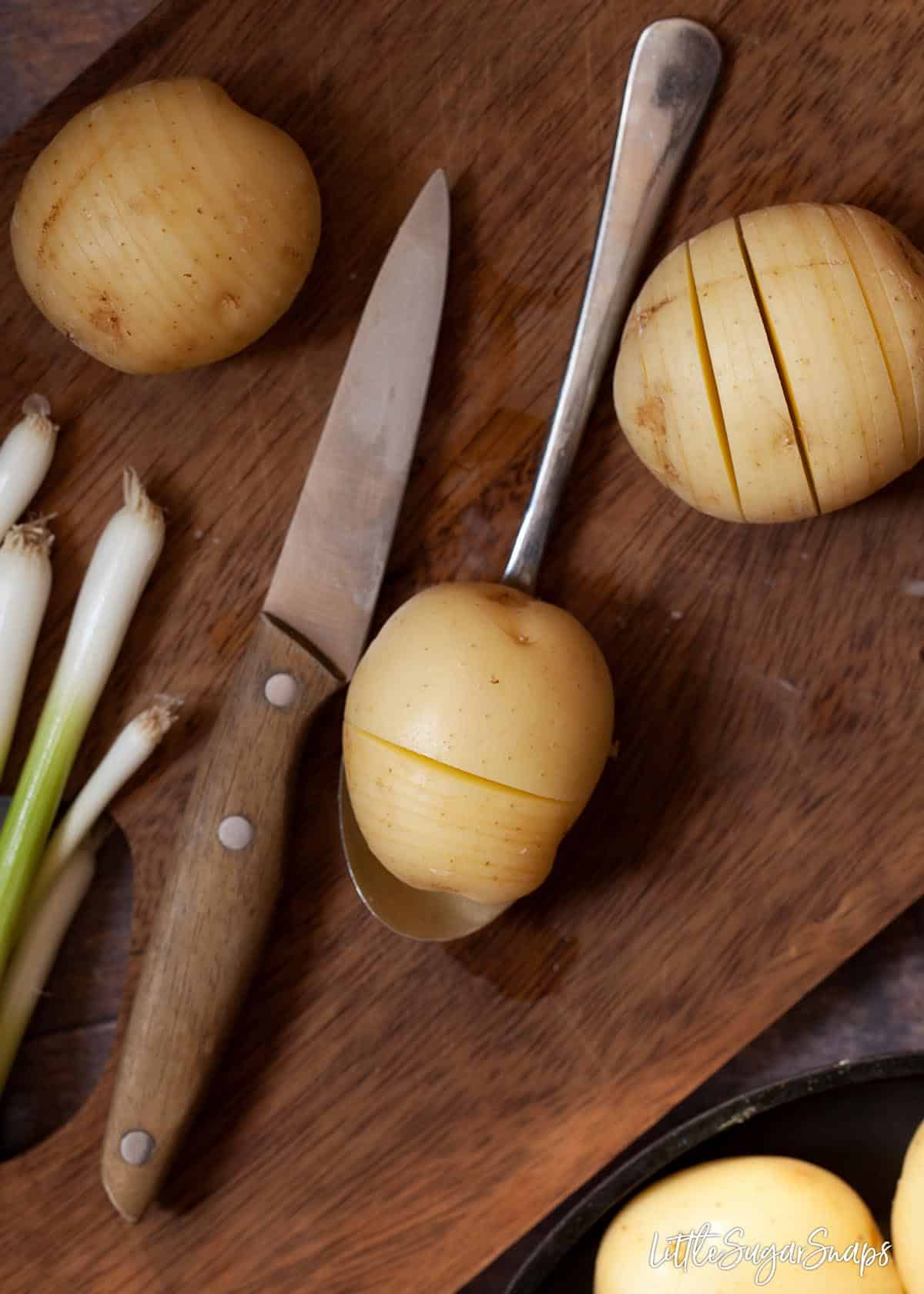 Process shot for Hasselback potatoes - cutting vertical slits into new potatoes using a metal spoon as a guide