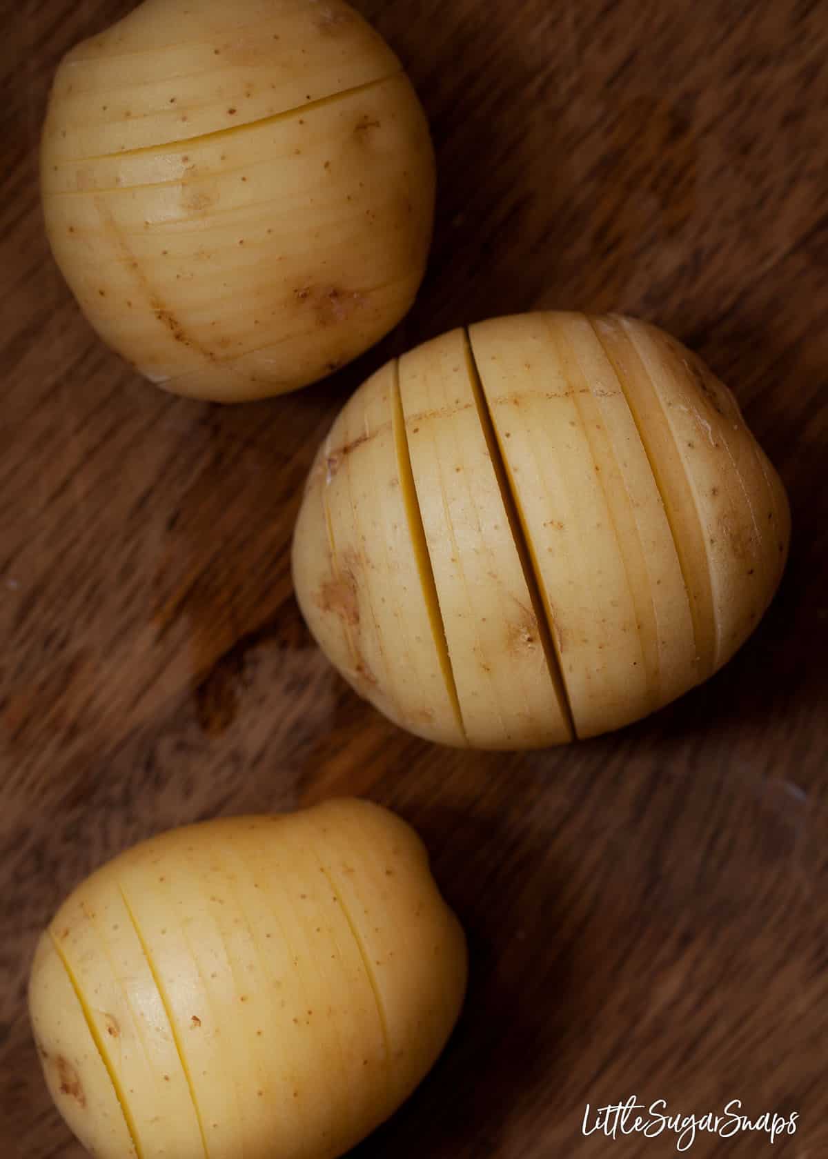 Process shot - new potatoes with vertical slits cut into them