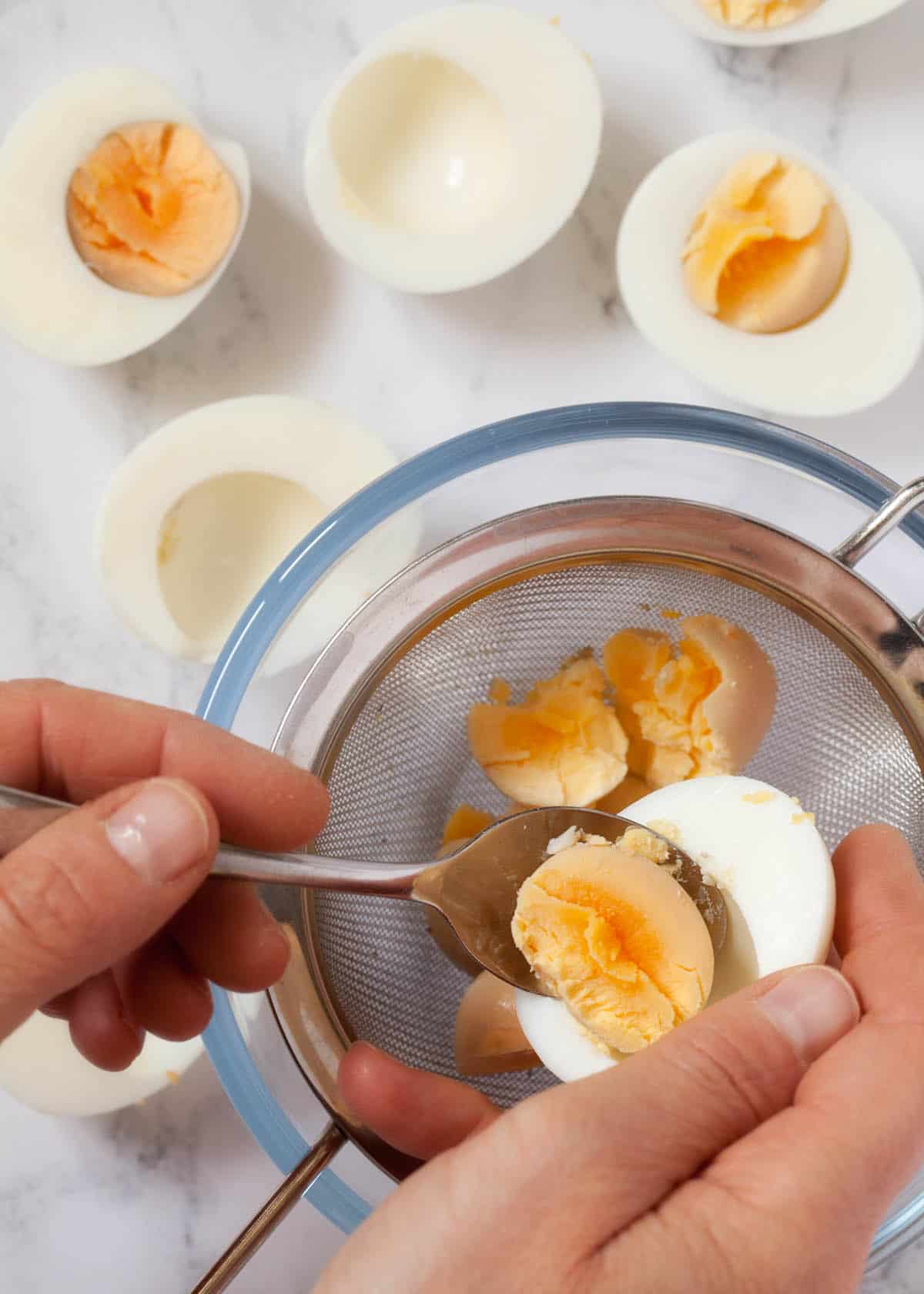 Scooping the yolks out of hard boiled eggs using a teaspoon