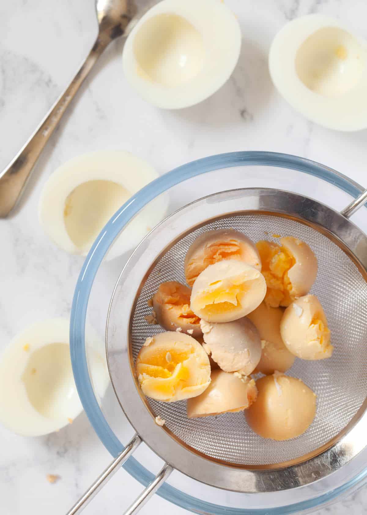 A sieve containing the yolks from some hard boiled eggs.