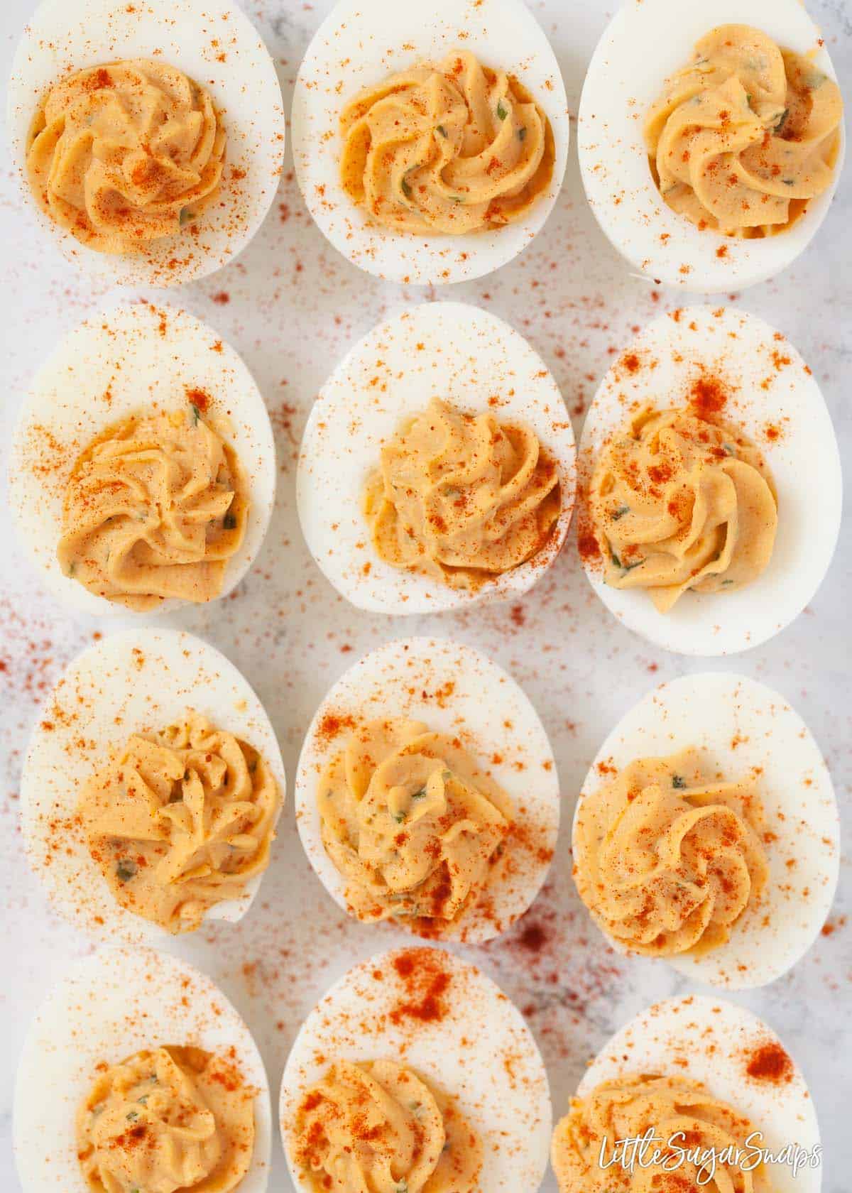 12 Devilled eggs on a worktop dusted with paprika