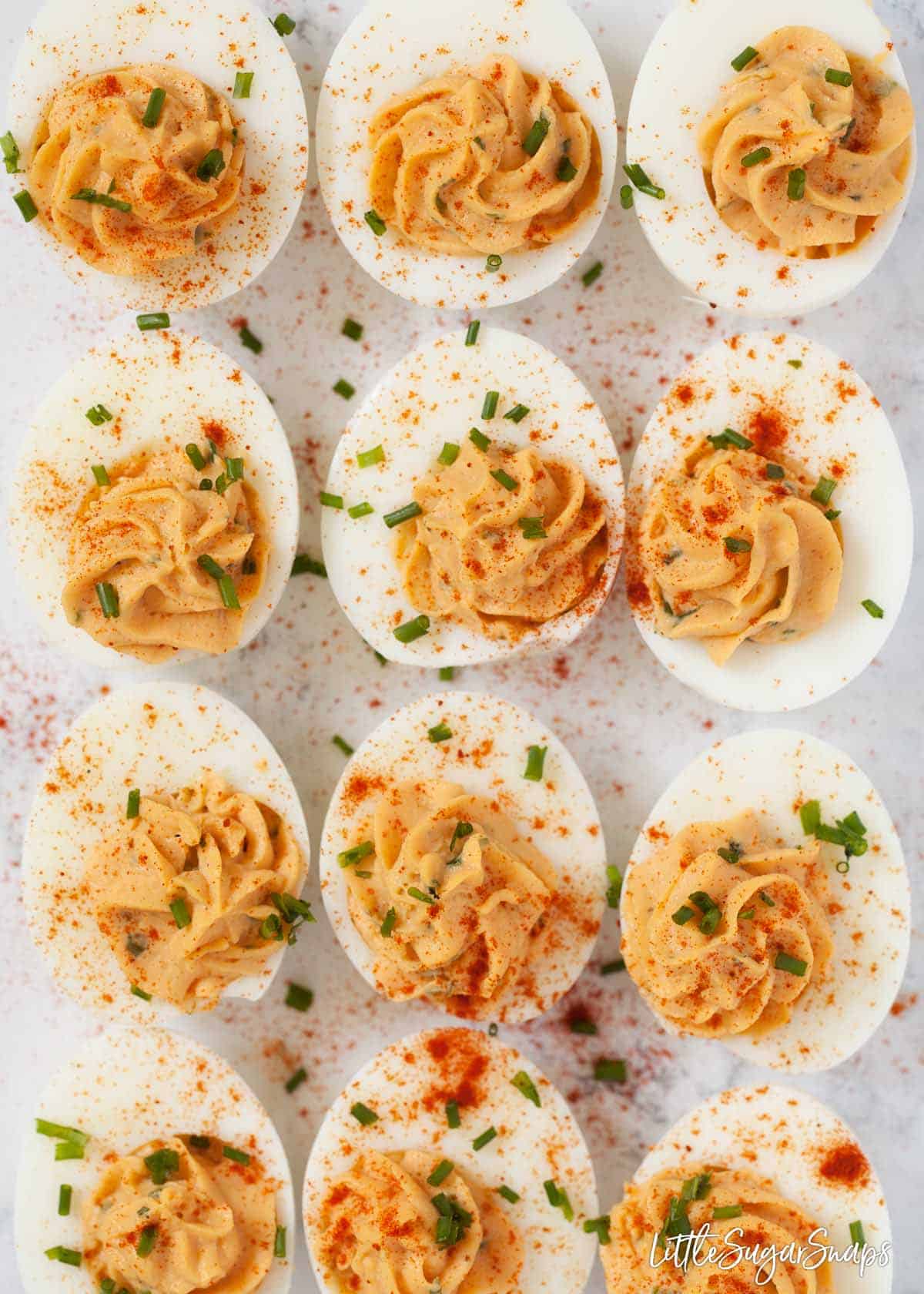 Devilled eggs on a worktop topped with paprika and chopped chives