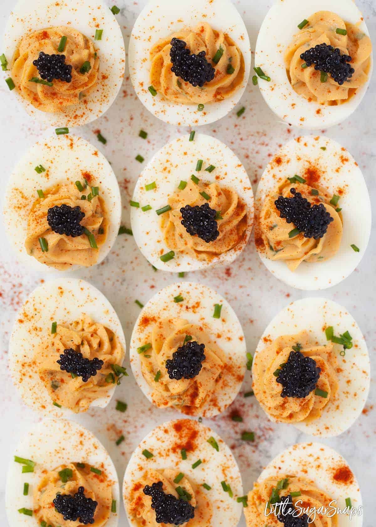 Devilled eggs topped with caviar, paprika and chives on a worktop