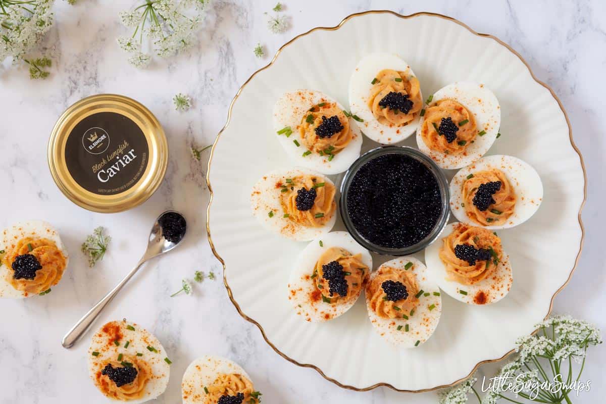 A plate of devilled eggs with caviar and unopened jars of caviar