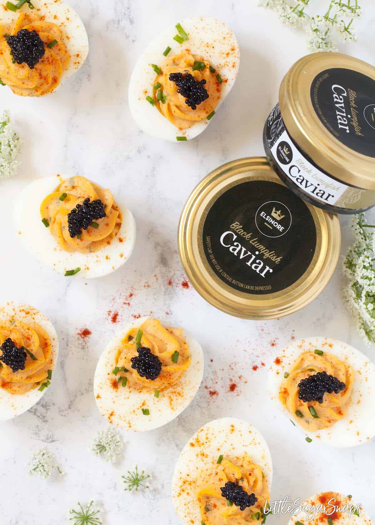 Devilled eggs with caviar on a worktop with unopened jars caviar alongside
