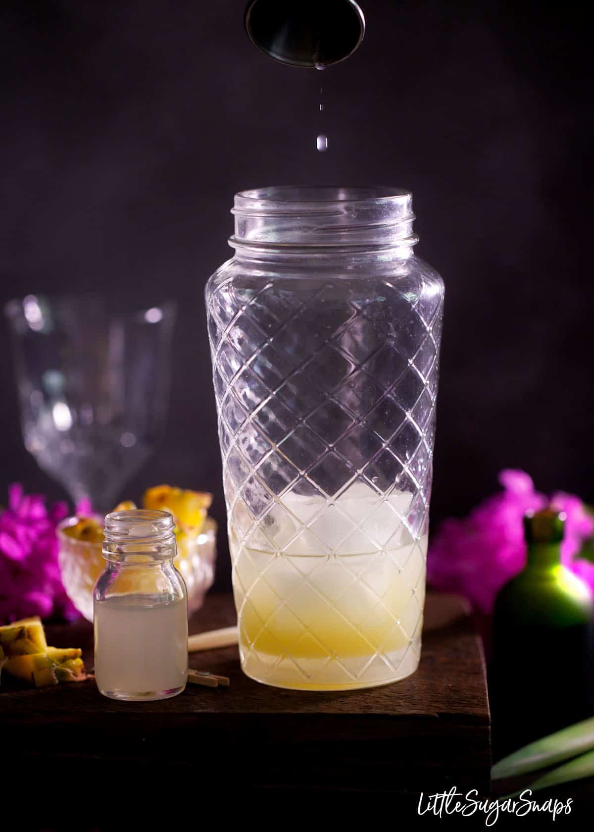 Adding a dash of orgeat syrup to a glass cocktail shaker