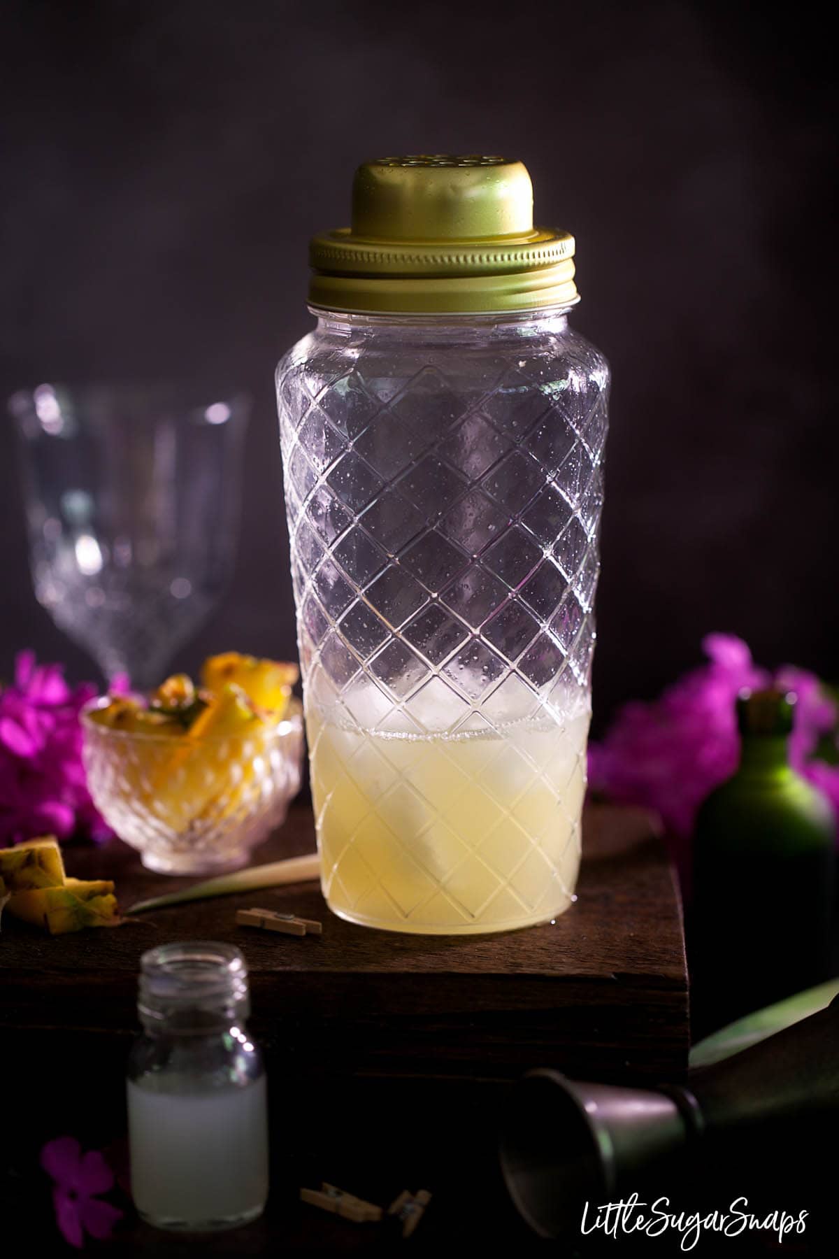 A gin and pineapple juice cocktail in a glass shaker freshly shaken
