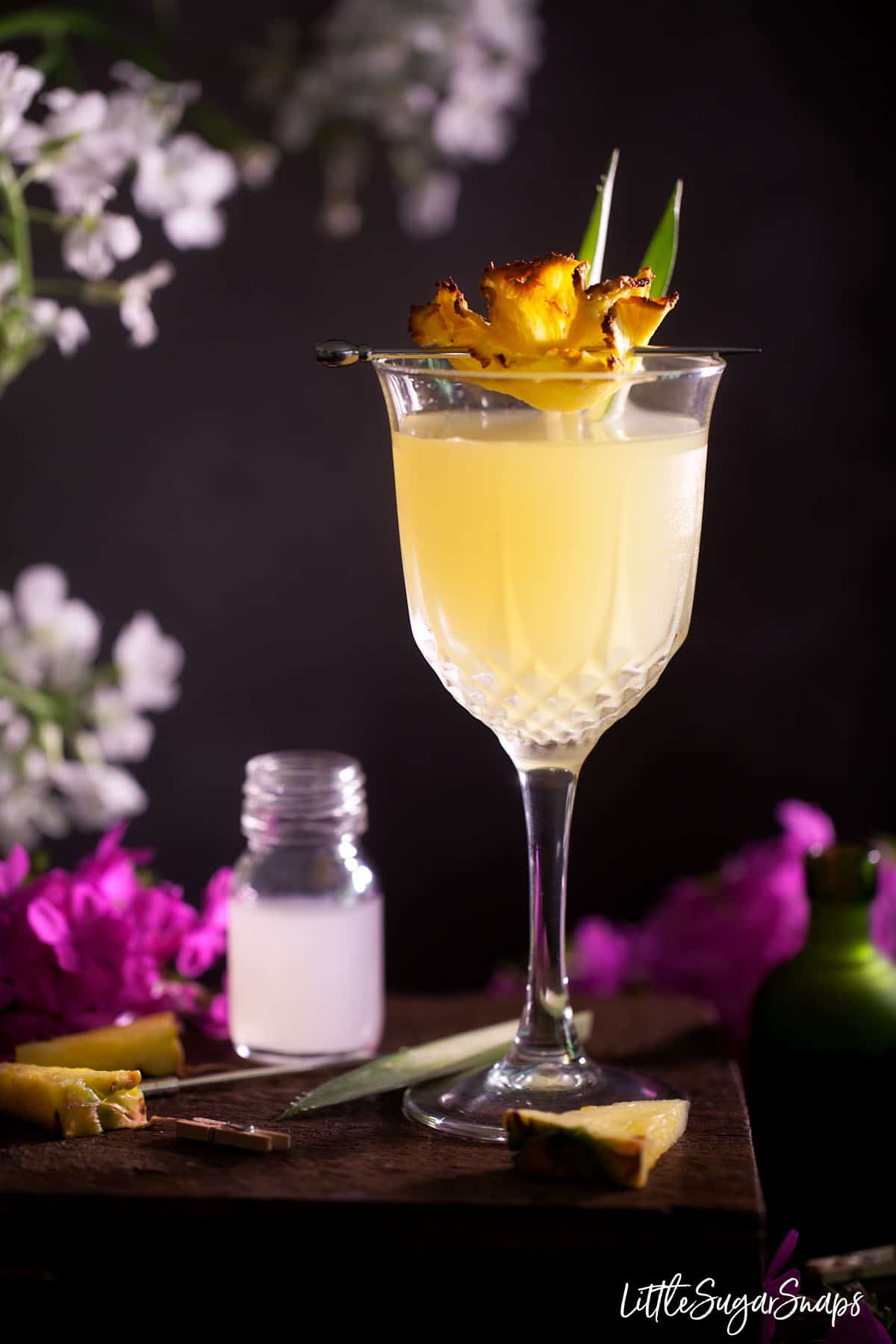 A Royal Hawaiian Cocktail garnished with dried pineapple and fresh pineapple leaves