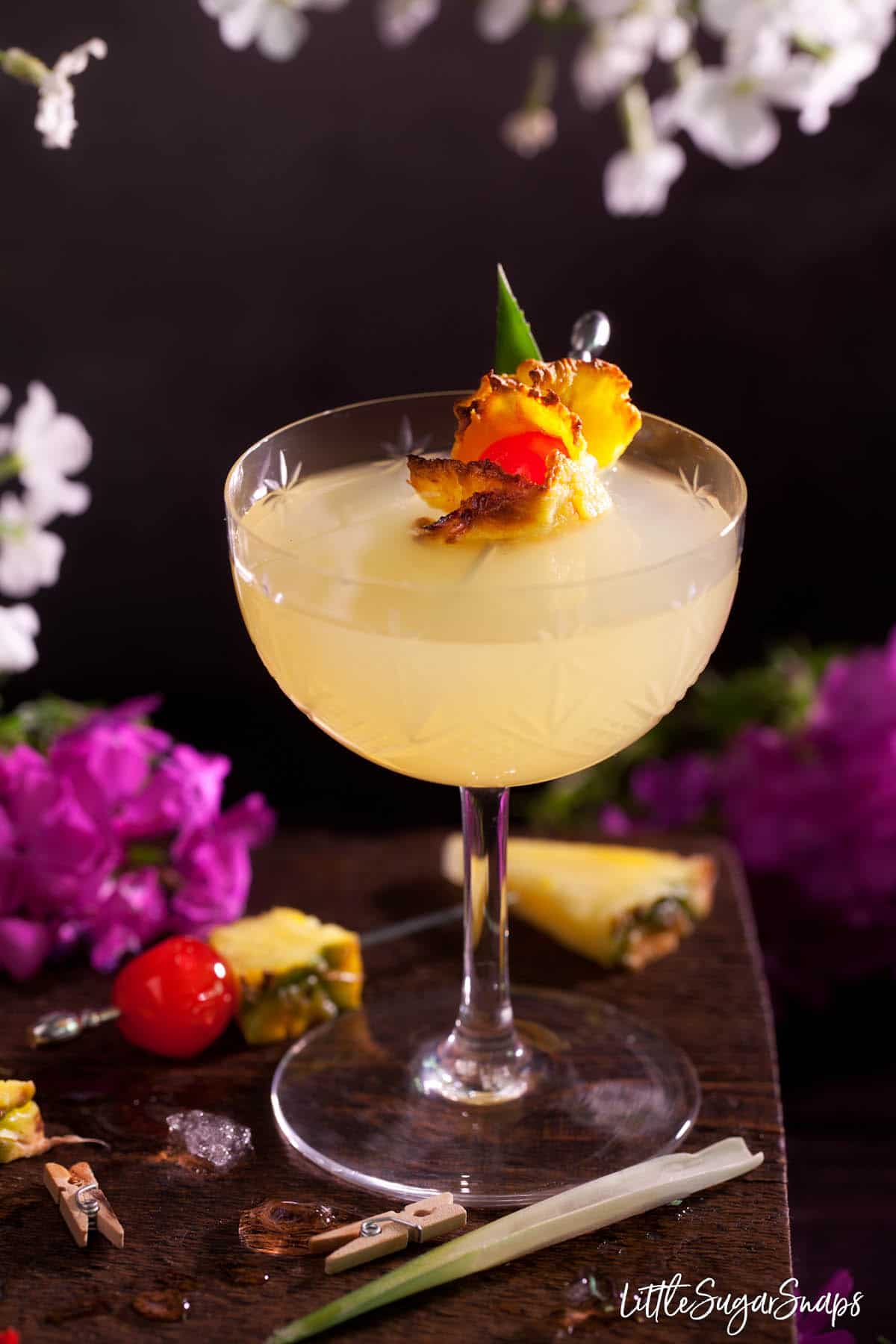 A Royal Hawaiian cocktail garnished with oven-dried pineapple and a maraschino cherry