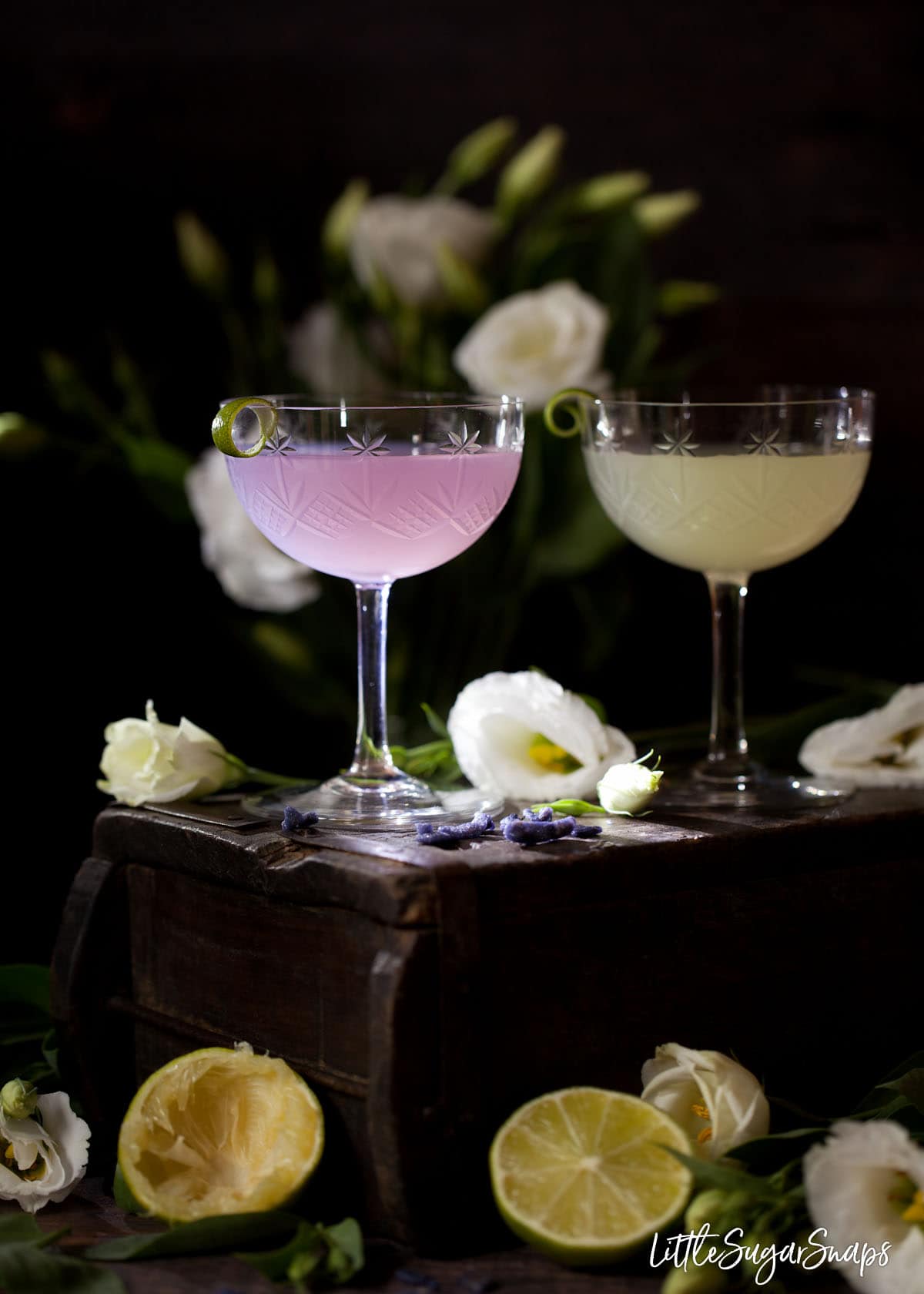 A classic daiquiri and a violet daiquiri cocktail on a wooden box.