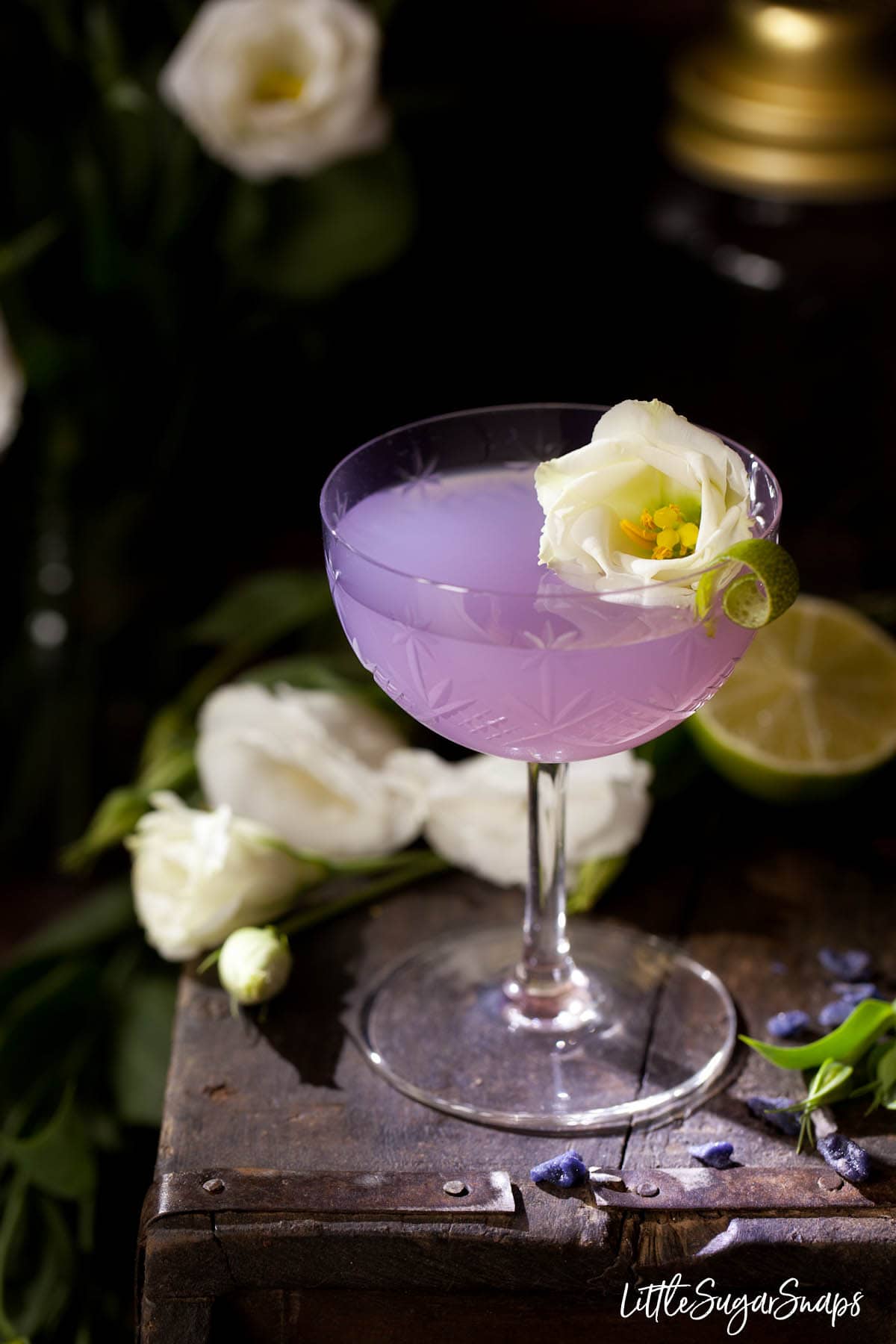 A purple coloured violet daiquiri cocktail with floral garnish