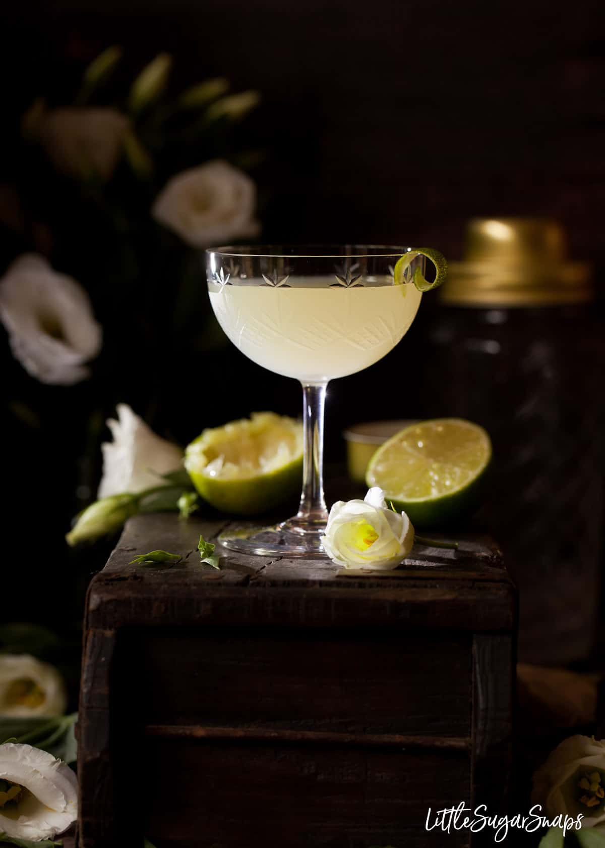 A classic daiquiri cocktail garnished with a curl of lime in a vintage glass