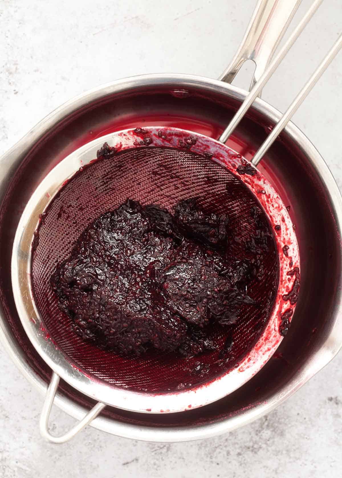 Straining Pulp after cooked blackcurrants have been strained through a sieve