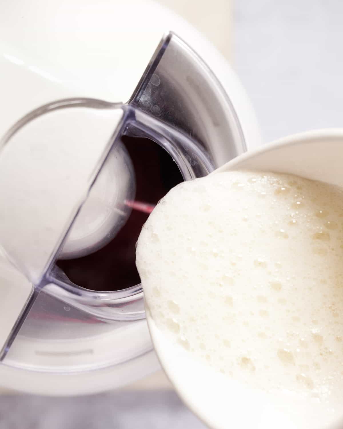 pouring egg white into an ice cream churner that is running