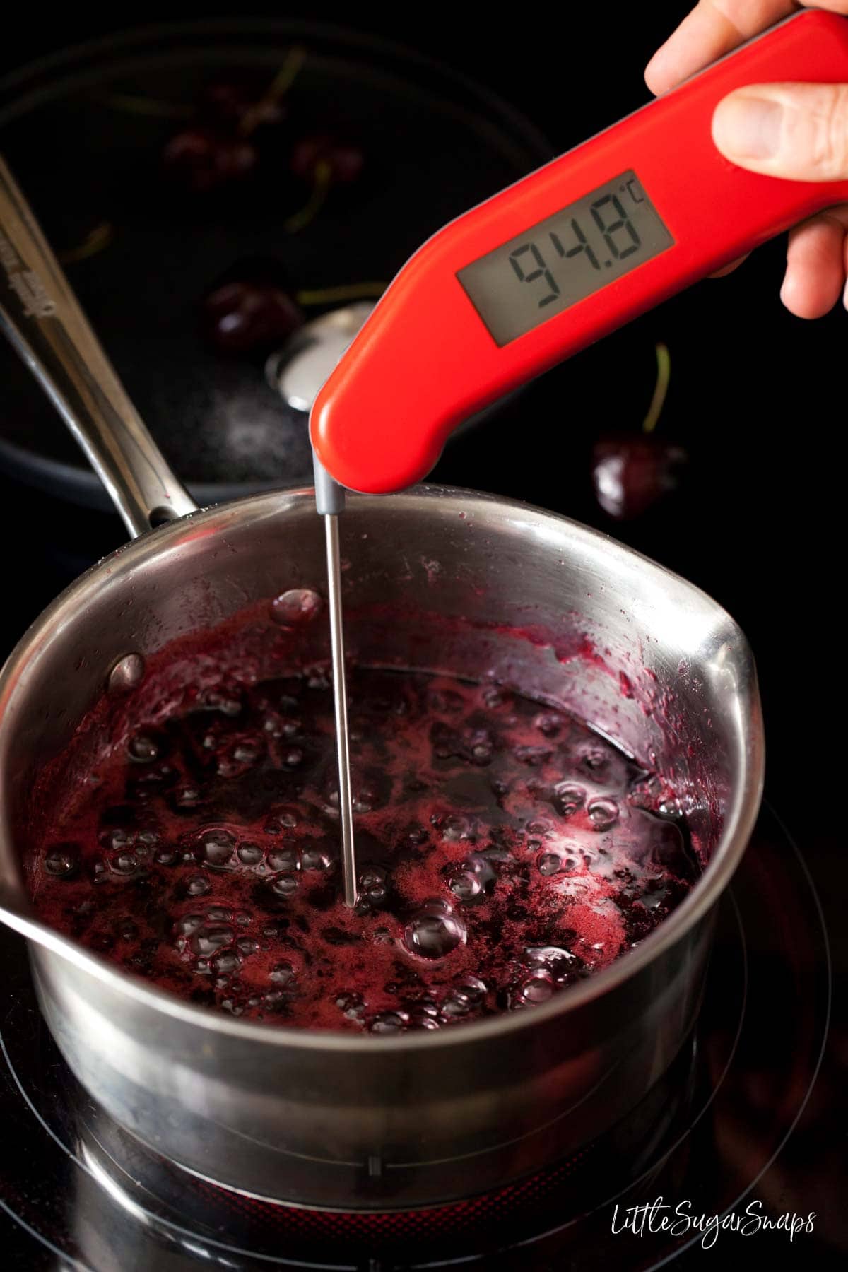 Testing the temperature of jam as it cooks with a food thermometer