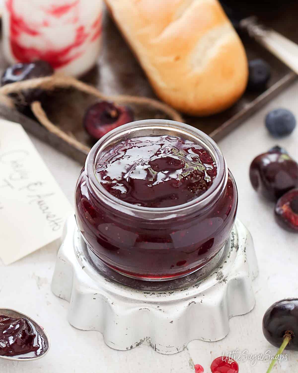 A jar of cherry jam flavoured with Amaretto on an upturned tart tin