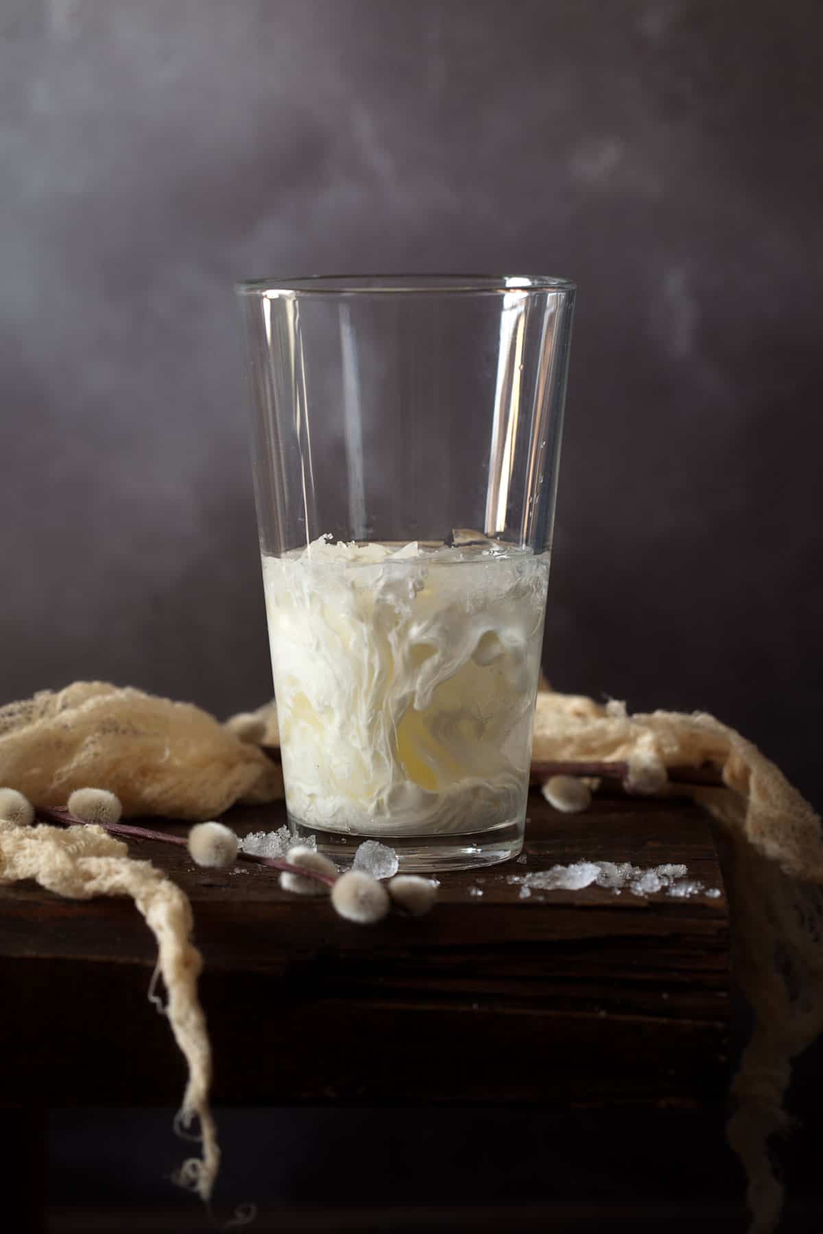 Adding cream to ingredients for a cocktail in a shaker filled with ice