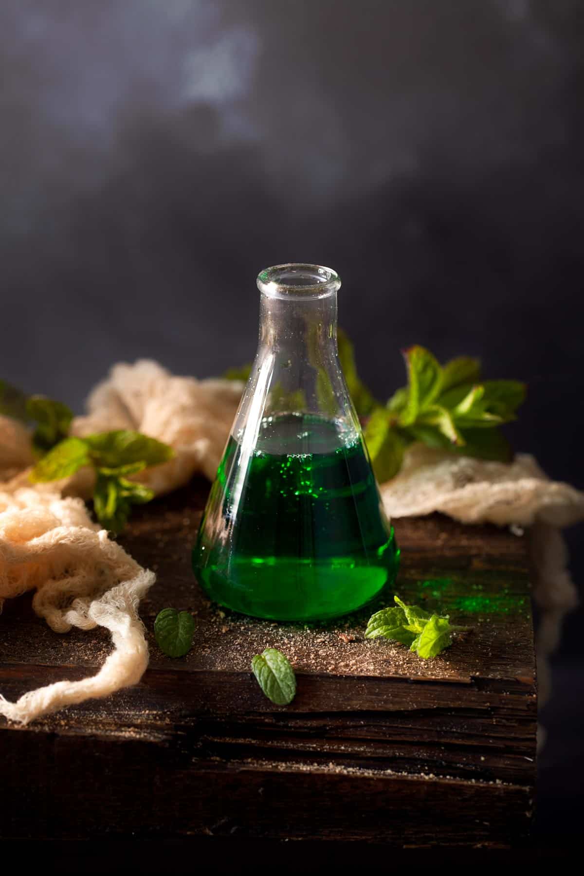 Small bottle of green creme de menthe liqueur on a wooden table 